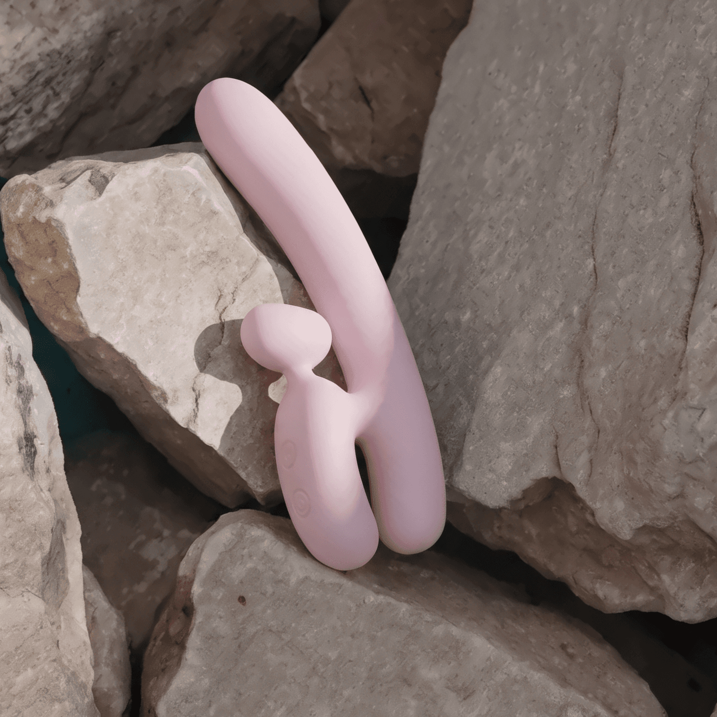 A pale pink dual vibrator propped between sunlit limestone rocks