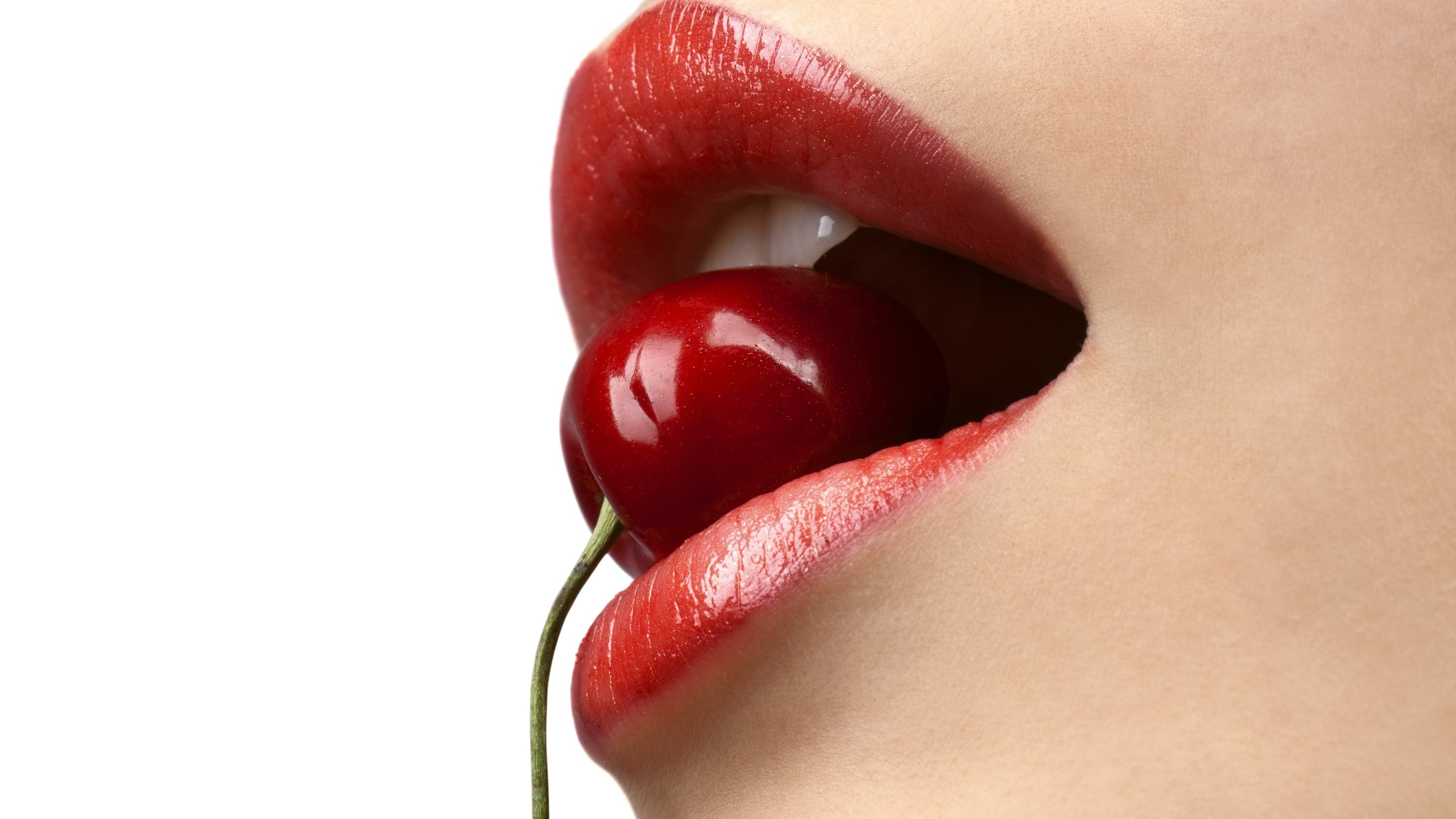 Red lips holding a cherry by its stem, against a white background
